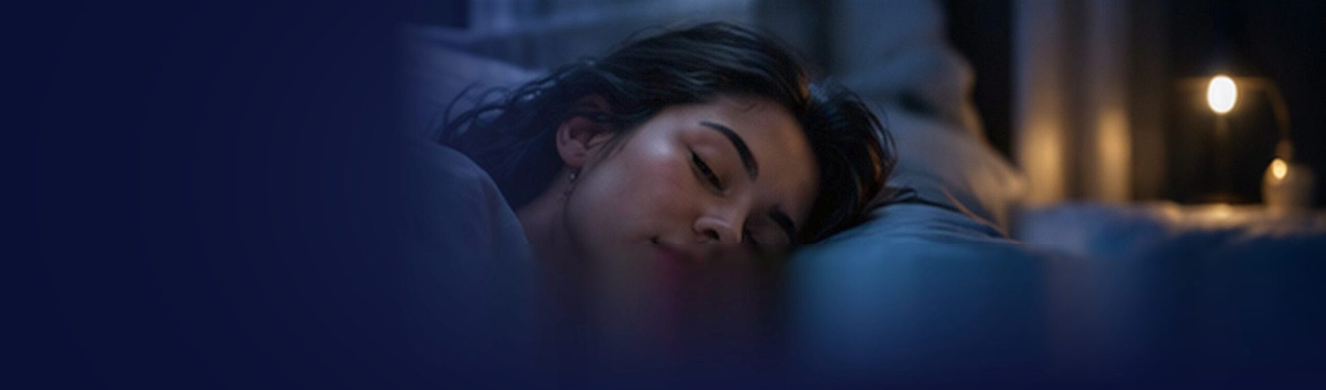 Une femme endormie dans la pénombre bleutée d’une chambre